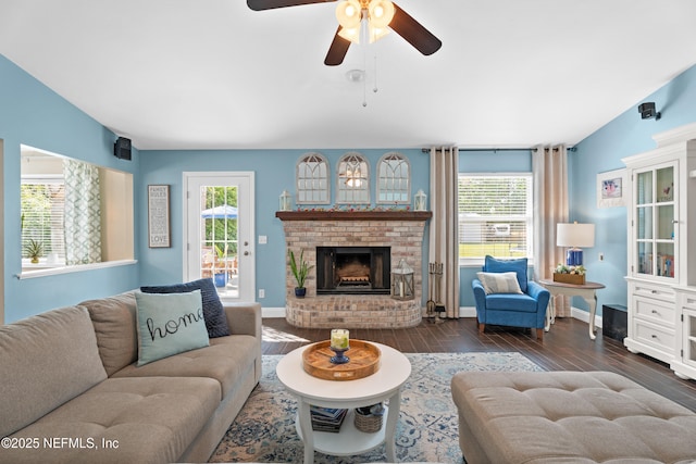 living room with wood finished floors, ceiling fan, baseboards, and a brick fireplace