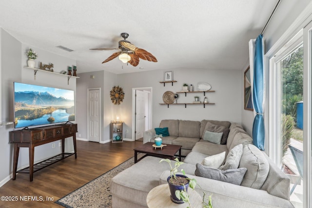 living area featuring dark wood-type flooring, ceiling fan, visible vents, and baseboards