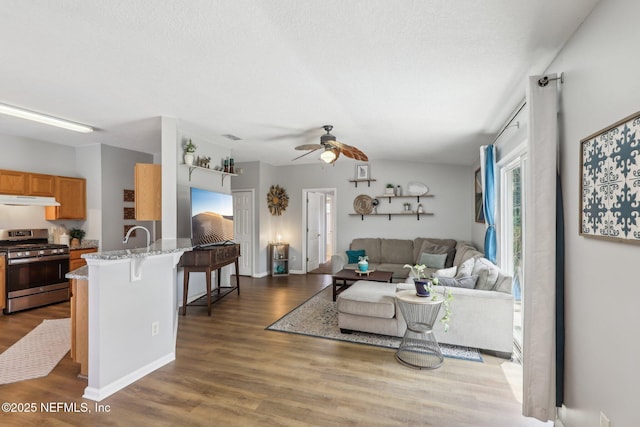 living area featuring baseboards, ceiling fan, and dark wood-style flooring