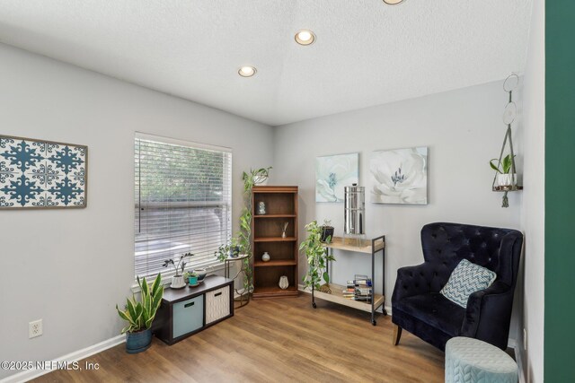 living area featuring recessed lighting, a textured ceiling, light wood-style flooring, and baseboards