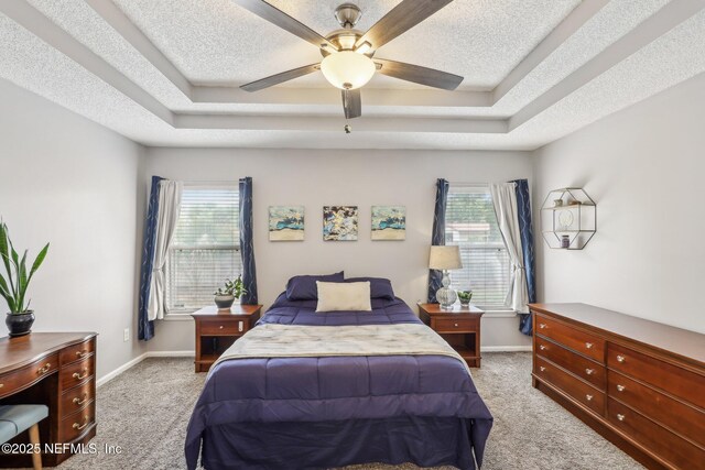 bedroom featuring a tray ceiling, carpet flooring, and multiple windows