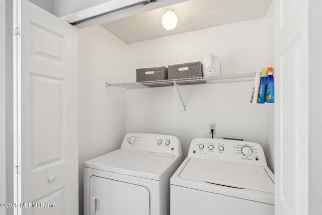 washroom with a textured ceiling, washing machine and clothes dryer, and laundry area