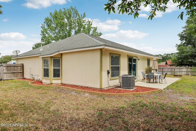 rear view of property with fence, cooling unit, a lawn, and a patio