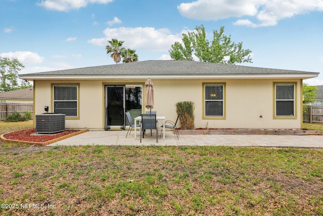 rear view of house featuring a patio, central AC unit, a yard, stucco siding, and fence