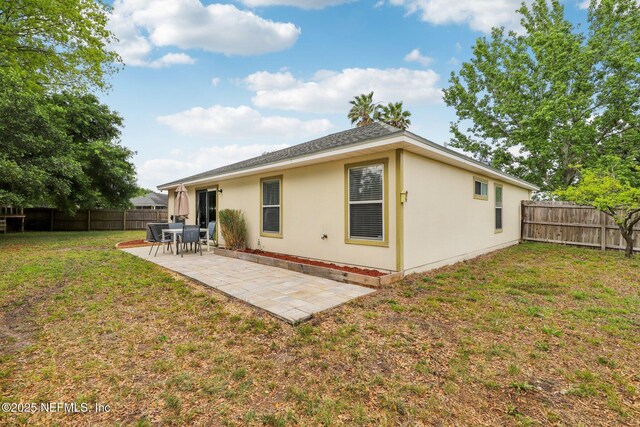 back of house featuring a yard, stucco siding, a fenced backyard, and a patio area