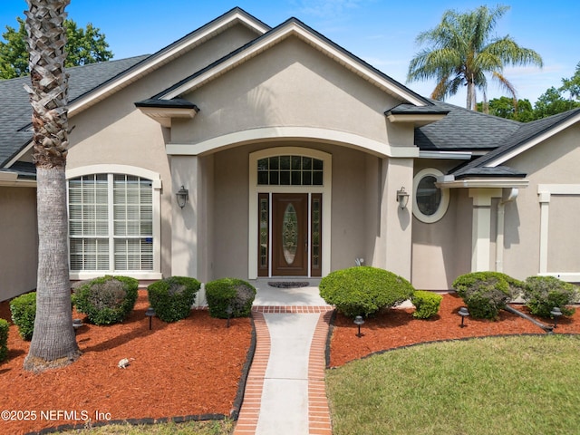 entrance to property with stucco siding and roof with shingles