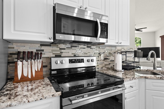 kitchen with white cabinetry, stainless steel appliances, decorative backsplash, and a sink