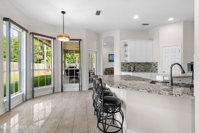 kitchen featuring decorative backsplash, open shelves, white cabinets, a sink, and visible vents