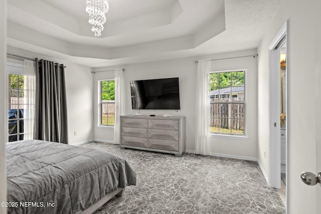 bedroom featuring an inviting chandelier, a raised ceiling, carpet flooring, and multiple windows