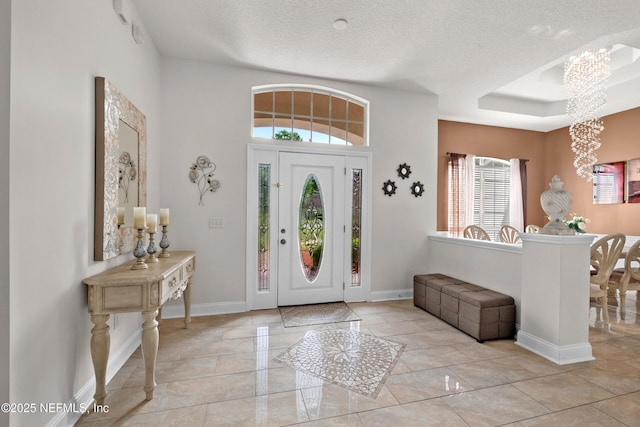 foyer featuring baseboards, a healthy amount of sunlight, and a textured ceiling