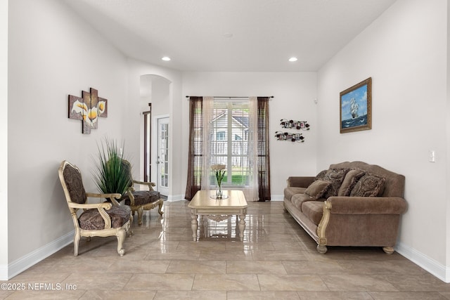 living area featuring baseboards, recessed lighting, and arched walkways