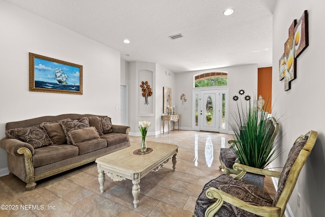 living area with baseboards, visible vents, a textured ceiling, and recessed lighting
