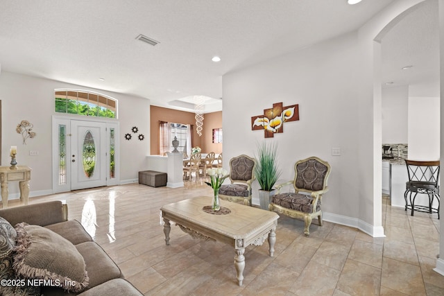 living area featuring baseboards, visible vents, arched walkways, and recessed lighting
