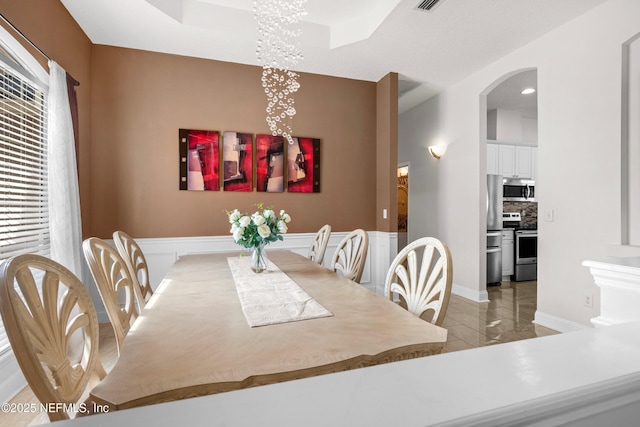 dining area featuring a chandelier, arched walkways, and light tile patterned flooring