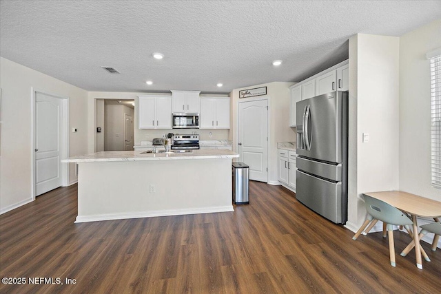 2294 Falling Star Ln, Green Cove Springs, FL 32043 - kitchen featuring appliances with stainless steel finishes, dark wood-style flooring, white cabinets, a kitchen island with sink, and recessed lighting