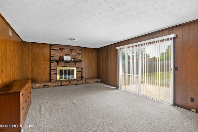 unfurnished living room with carpet flooring, a textured ceiling, and wooden walls