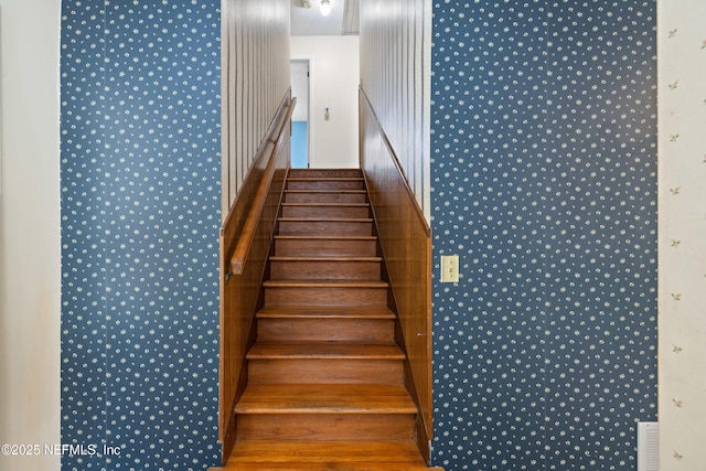 stairway with wallpapered walls and visible vents
