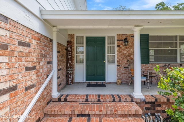 doorway to property with a porch and brick siding