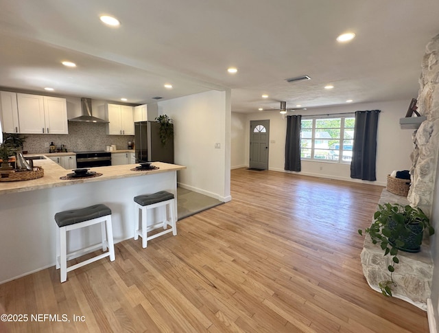 1118 Brookmont Ave E, Jacksonville, FL 32211 - kitchen featuring wall chimney range hood, freestanding refrigerator, a peninsula, light wood-type flooring, and recessed lighting