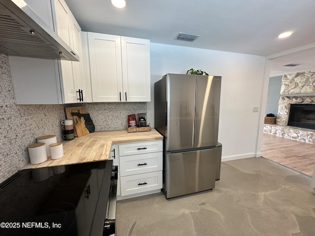 1118 Brookmont Ave E, Jacksonville, FL 32211 - kitchen with freestanding refrigerator, range hood, white cabinetry, backsplash, and black range with electric stovetop