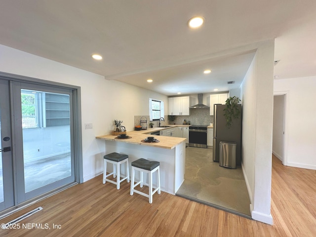 1118 Brookmont Ave E, Jacksonville, FL 32211 - kitchen with stove, a peninsula, wall chimney exhaust hood, light wood-style flooring, and recessed lighting