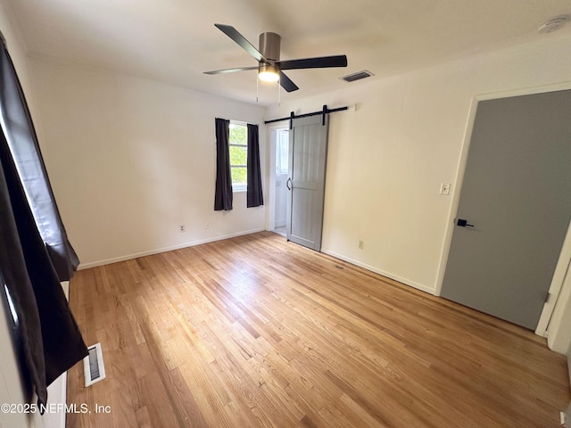 1118 Brookmont Ave E, Jacksonville, FL 32211 - unfurnished bedroom with light wood-style flooring, a barn door, and a ceiling fan