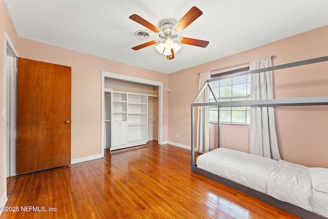 bedroom featuring wood finished floors, a closet, visible vents, and baseboards
