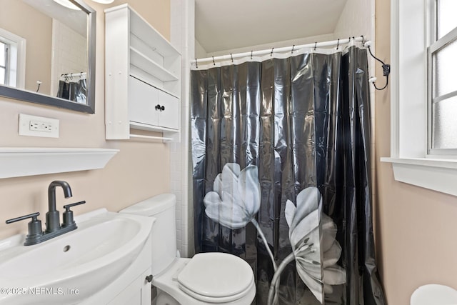 bathroom with curtained shower, toilet, and a sink