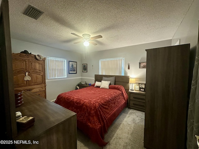 bedroom featuring a textured ceiling, visible vents, a ceiling fan, and light colored carpet
