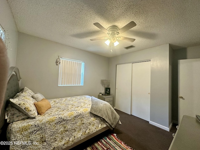 bedroom featuring dark carpet, a textured ceiling, visible vents, a closet, and a ceiling fan