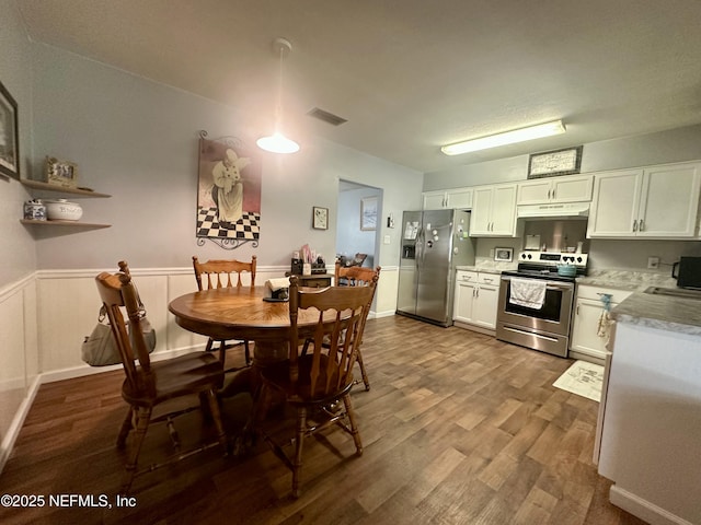dining room featuring dark wood-type flooring, visible vents, and wainscoting