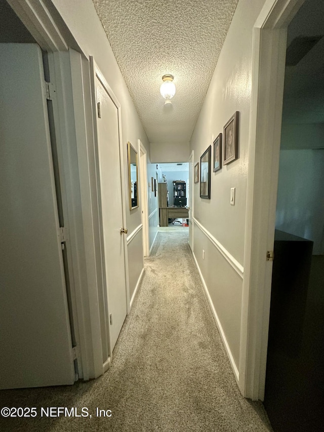 hallway featuring a textured ceiling and carpet floors