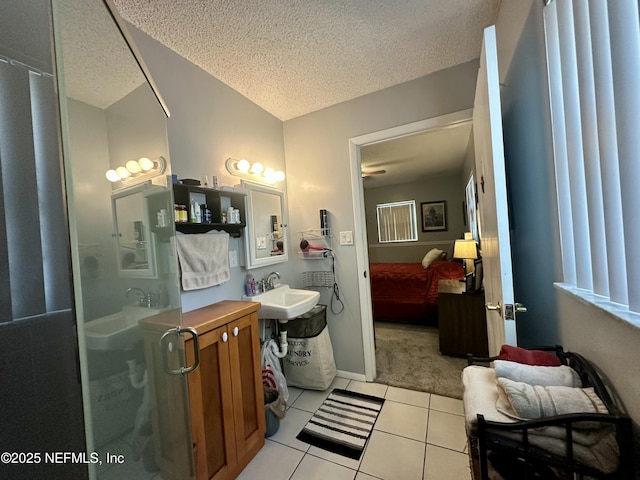 full bathroom with tile patterned floors, a textured ceiling, a stall shower, and a sink