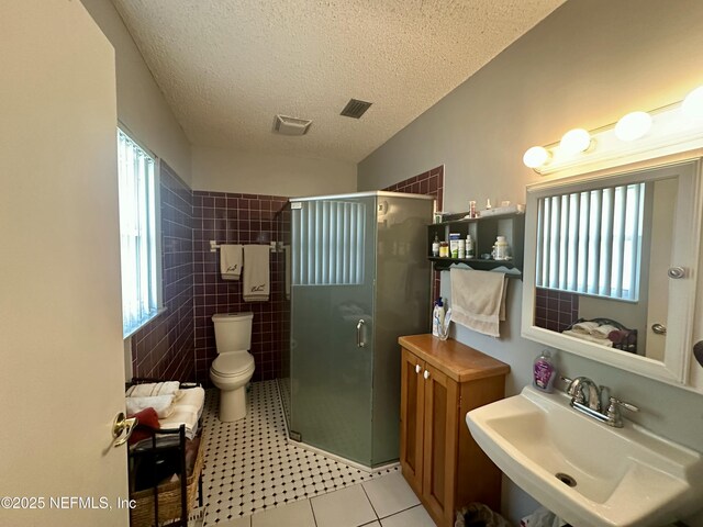 bathroom with a sink, a shower stall, tile patterned floors, toilet, and a textured ceiling
