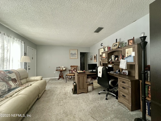 office featuring a textured ceiling, visible vents, and light carpet