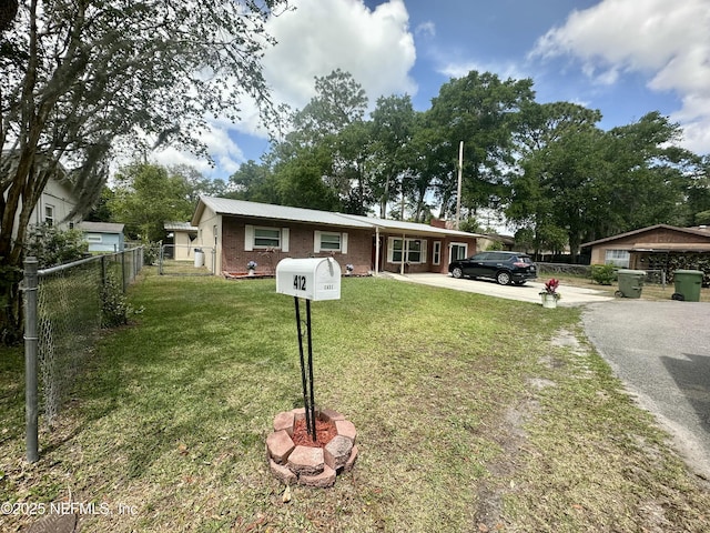 view of front of property with brick siding, fence, a front lawn, and driveway