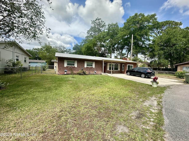 ranch-style home with brick siding, fence, metal roof, driveway, and a front lawn