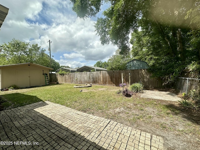 view of yard with a patio, a fenced backyard, an outbuilding, and a storage shed