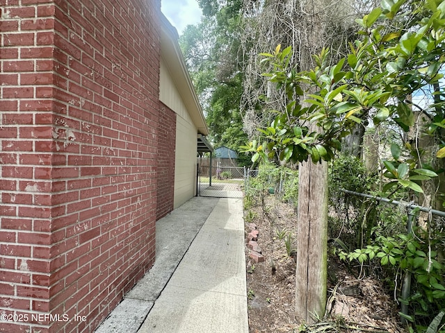 view of property exterior with brick siding, fence, and a gate