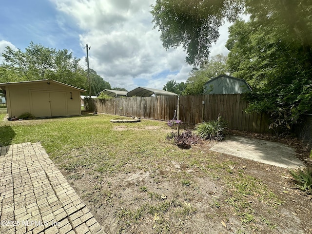 view of yard featuring a storage unit, a patio area, an outbuilding, and a fenced backyard