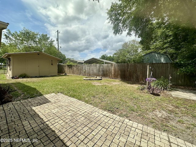 view of yard featuring a storage unit, a patio area, an outdoor structure, and a fenced backyard