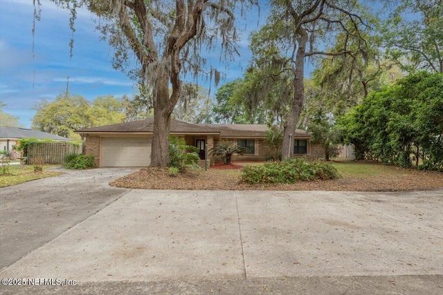ranch-style house featuring an attached garage, fence, and driveway