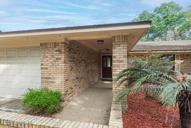 entrance to property featuring a garage and brick siding