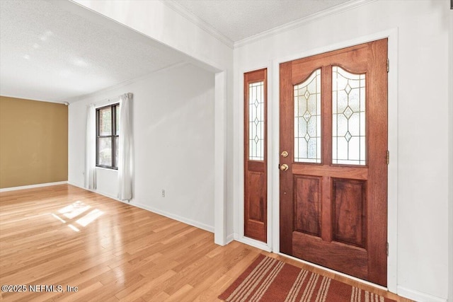 foyer with a textured ceiling, ornamental molding, baseboards, and light wood finished floors