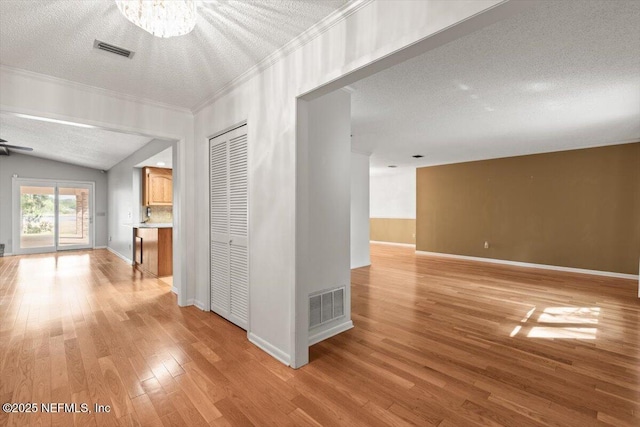 hall featuring crown molding, a textured ceiling, visible vents, and light wood finished floors