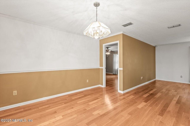 unfurnished room featuring crown molding, light wood-style floors, ceiling fan with notable chandelier, and visible vents