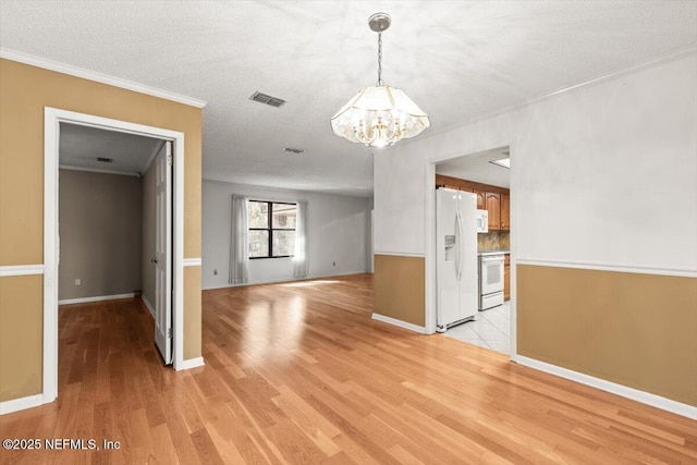 unfurnished dining area featuring visible vents, baseboards, a chandelier, light wood-style floors, and ornamental molding