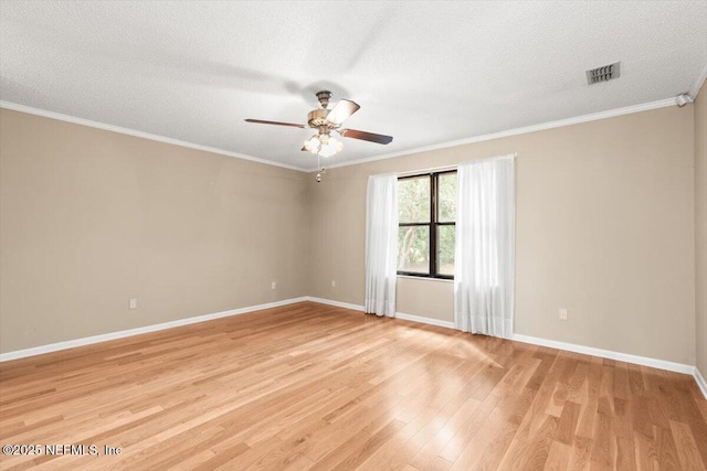 unfurnished room featuring light wood finished floors, a ceiling fan, baseboards, visible vents, and ornamental molding