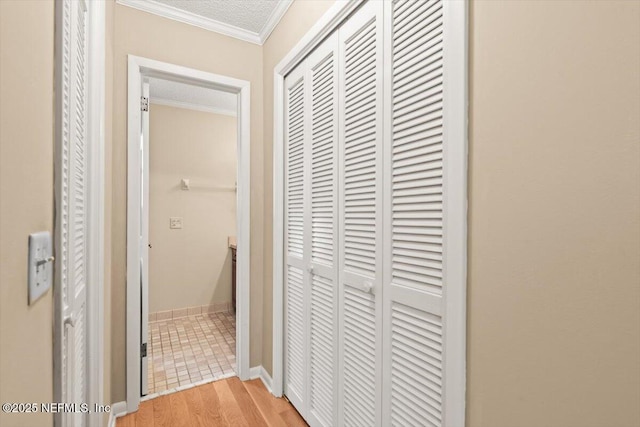 corridor with ornamental molding and light wood-type flooring