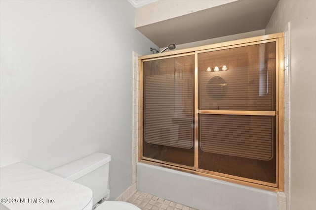full bath with tile patterned flooring, ornamental molding, combined bath / shower with glass door, and toilet